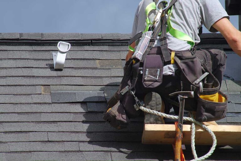 Roofers inspect attic insulation and ventilation beneath a newly replaced residential roof.